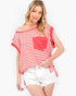 A woman modeling a red and white striped off-the-shoulder top with a solid red chest pocket, paired with white denim shorts, against a plain white background.