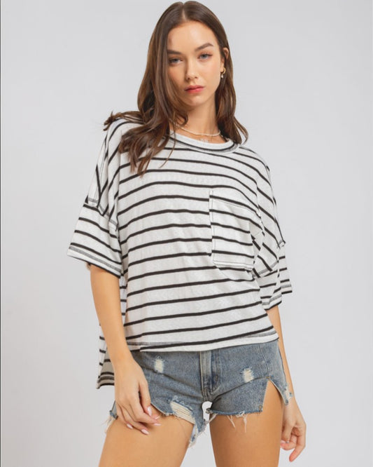 Woman wearing a black and white striped shirt with denim shorts on a plain background
