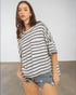 Woman wearing a black and white striped shirt and denim shorts against a plain background