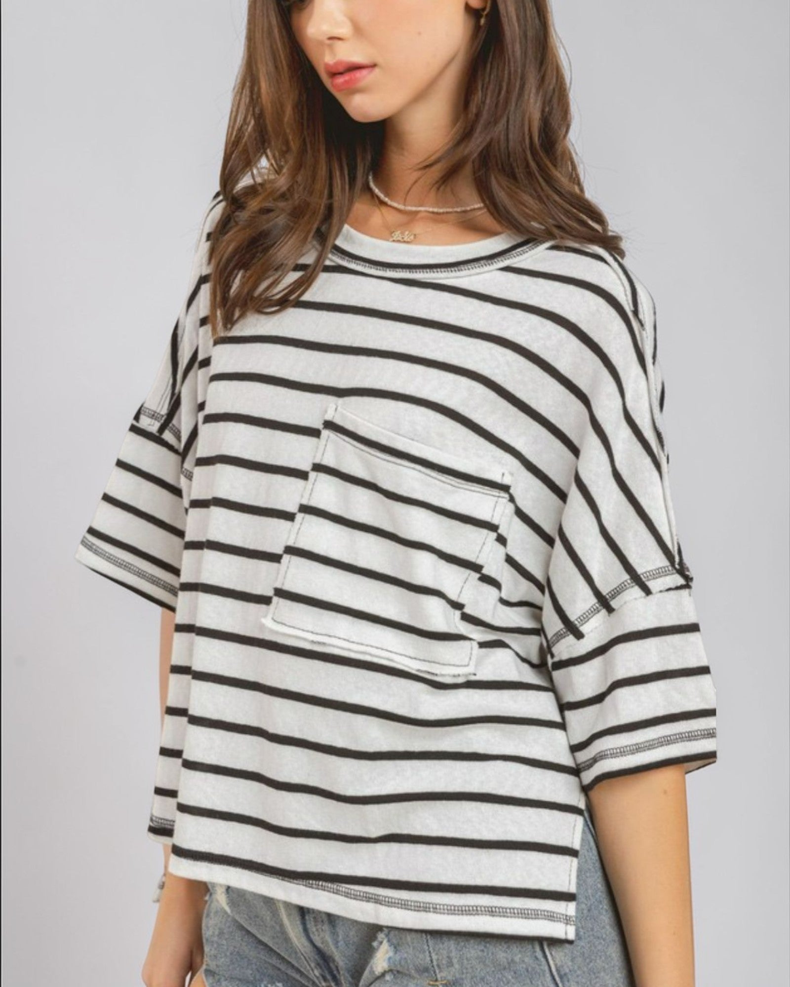 Woman wearing a striped shirt with a pocket on a plain background
