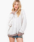 A woman modeling a long-sleeve, off-the-shoulder striped top with a crew neck and ribbed cuffs and hem, paired with denim shorts against a plain white background.