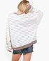 A woman shown from the back wearing a loose, long-sleeve striped sweatshirt with a taupe ribbed crew neck, cuffs, and hem, paired with denim shorts against a plain white background.