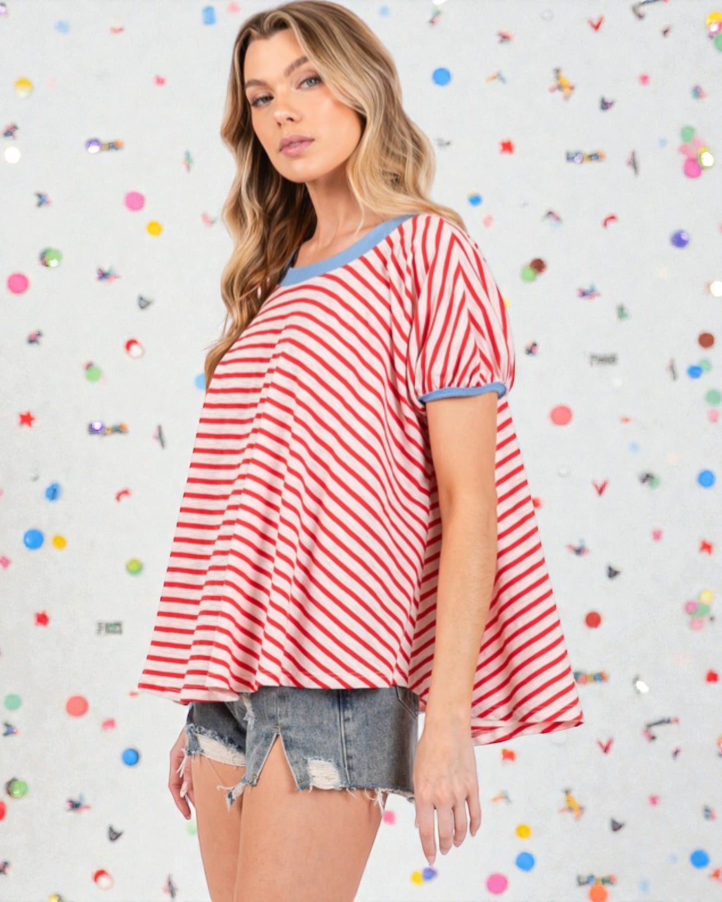 Woman wearing a red and white striped top with denim shorts against a colorful polka dot background