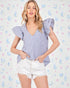 Woman wearing a blue and white striped top with puffed sleeves against a pastel patterned background