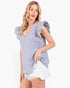 A woman modeling a light blue and white vertically striped top with ruffled cap sleeves, paired with white denim shorts, against a plain white studio background.