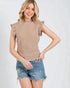 Woman wearing a beige textured top and denim shorts on a white background