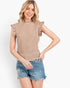 A woman modeling a sleeveless beige waffle-knit top with ruffle trim on the shoulders, paired with distressed denim shorts, against a plain white studio background.