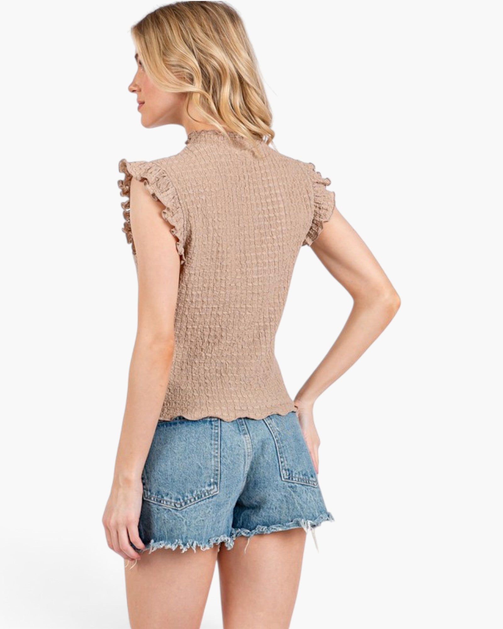 A woman shown from the back wearing a beige textured sleeveless top with ruffled trim and light blue denim shorts against a plain white background.