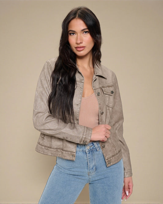 Woman wearing a beige jacket and blue jeans against a beige background