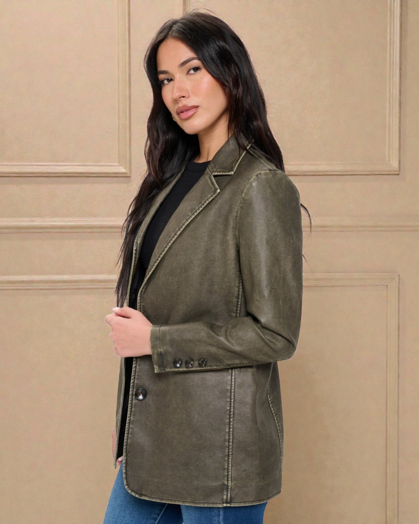 Woman wearing an olive green jacket against a beige wall