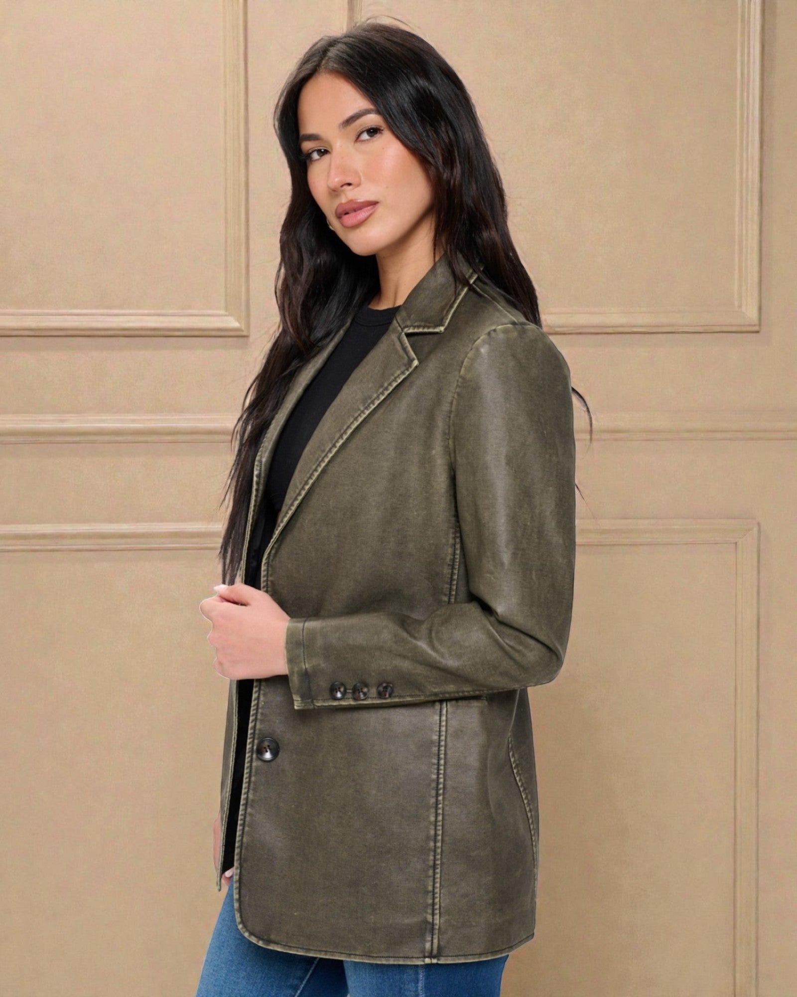 Woman wearing an olive green jacket against a beige wall