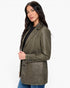 A woman modeling a double-breasted blazer in a washed olive green color, styled with a black top and blue jeans against a plain white background.