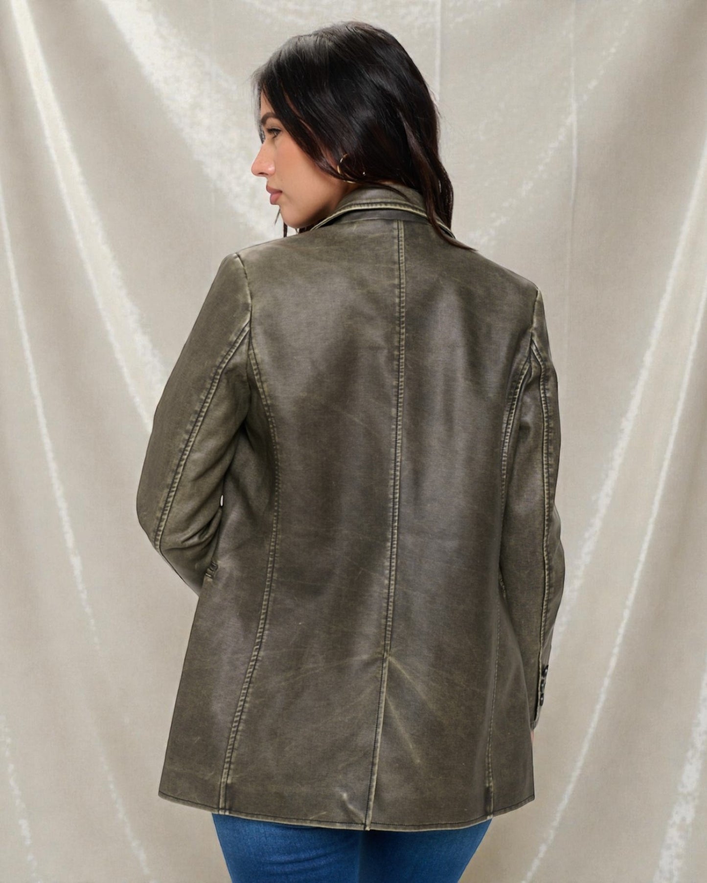 Person wearing a green leather jacket against a plain background