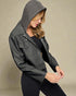 Woman wearing a gray hooded jacket against a beige background