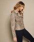 Woman wearing a beige leather jacket with studded details against a beige background