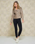 Woman wearing a beige leather jacket and black leggings against a neutral background