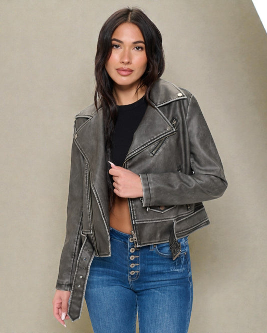 Woman wearing a gray leather jacket and blue jeans against a beige background