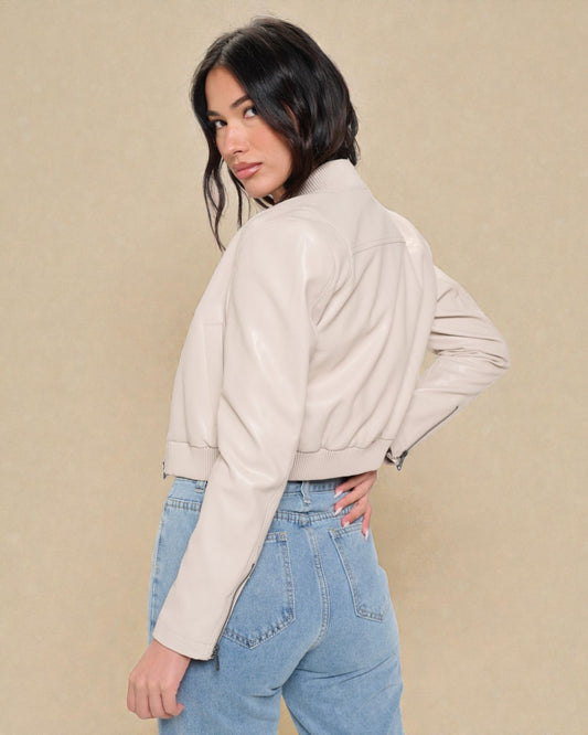 Woman wearing a beige jacket and blue jeans against a beige background