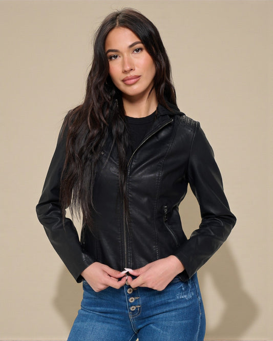 Woman wearing a black leather jacket and blue jeans against a beige background