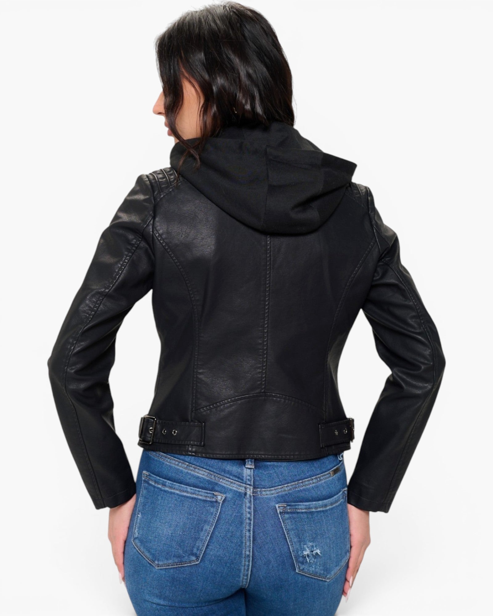 A woman shown from the back wearing a black faux-leather hooded moto jacket and blue jeans against a plain white background.