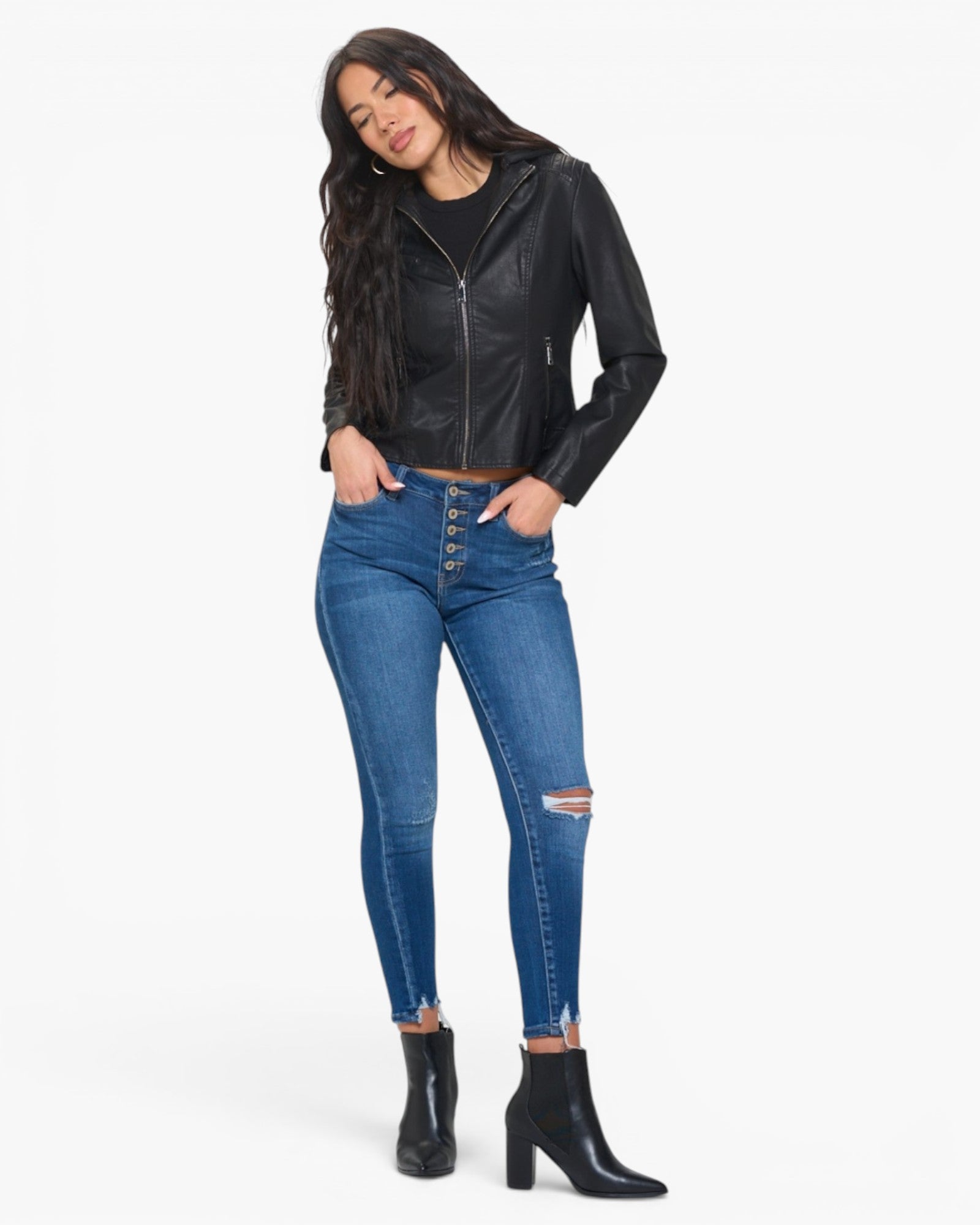 A woman modeling a black faux-leather zip-up jacket, blue high-waisted skinny jeans with distressed details, and black ankle boots against a plain white background.