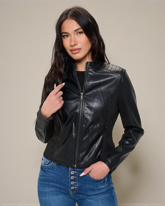 Woman wearing a black leather jacket and blue jeans against a beige background