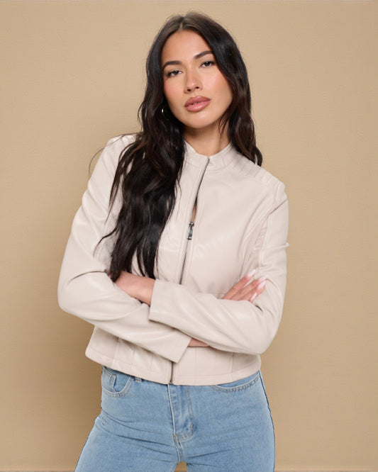 Woman wearing a beige jacket and blue jeans against a beige background