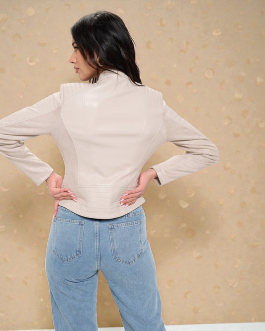 Person wearing a beige jacket and blue jeans against a beige background
