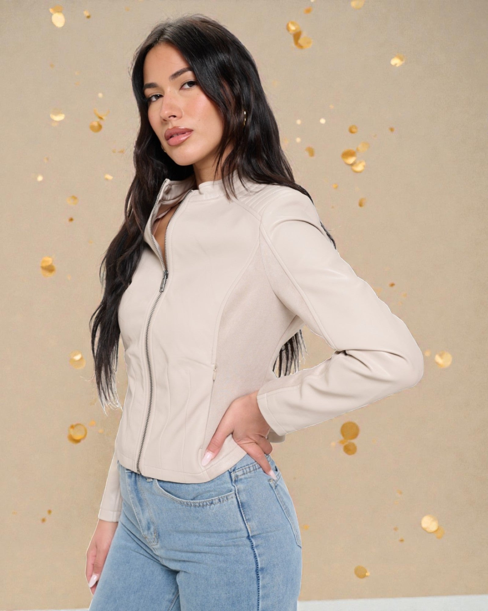 Woman wearing a beige jacket and blue jeans against a beige background with gold confetti.
