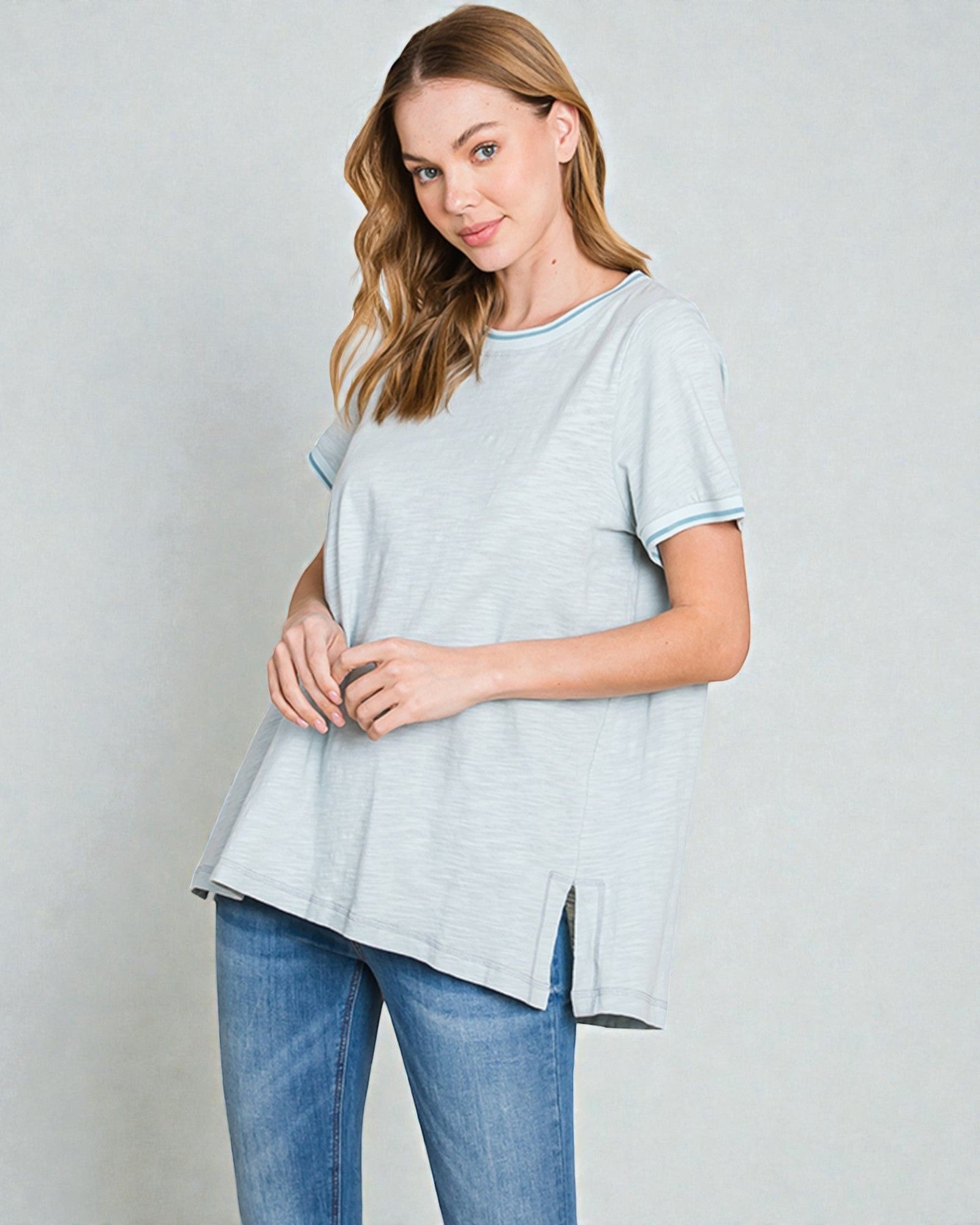 Woman wearing a light blue t-shirt and jeans on a plain background