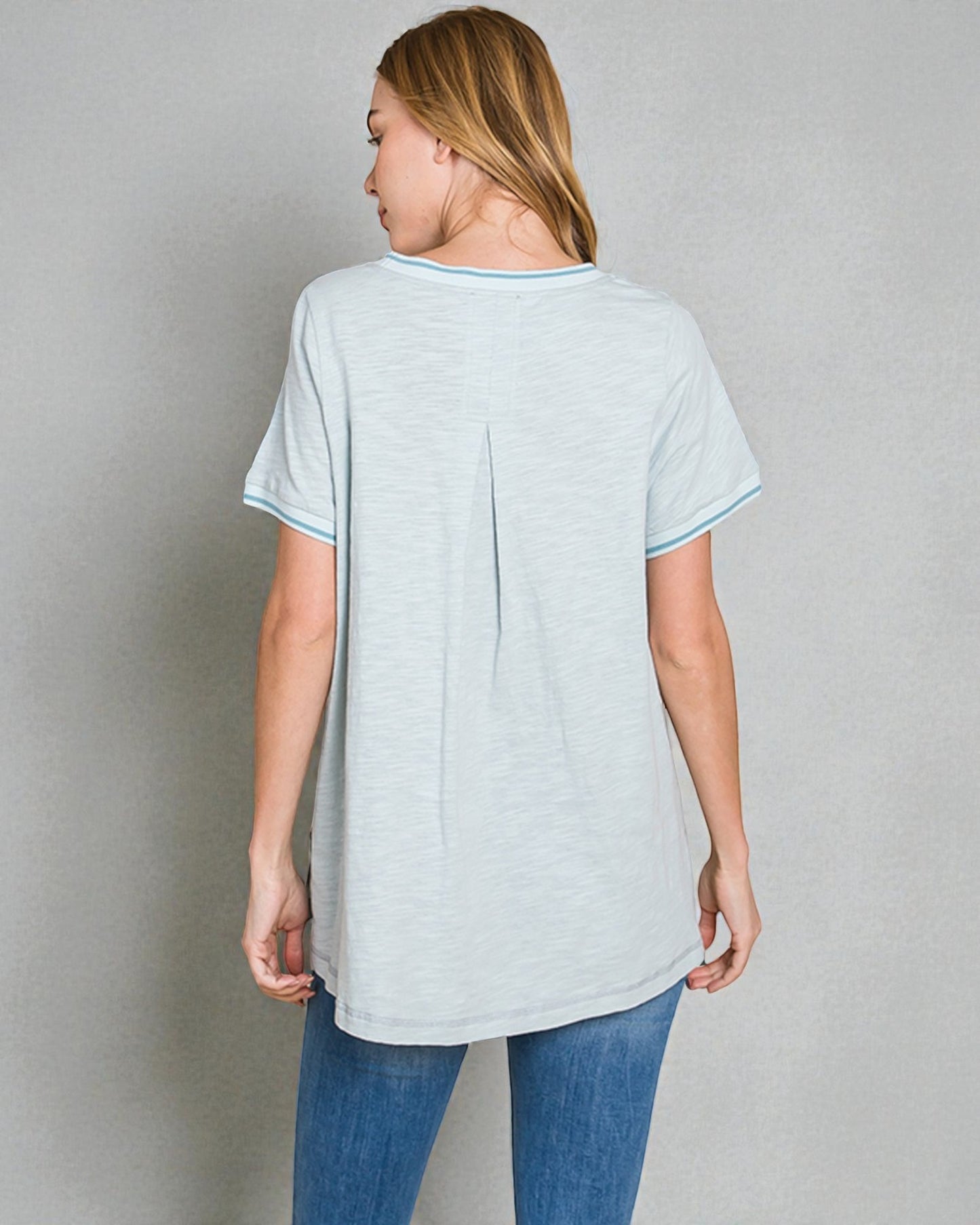 Woman wearing a light gray t-shirt and blue jeans against a plain background