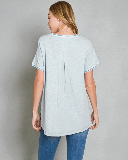 Woman wearing a light gray t-shirt and blue jeans against a plain background