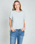 Woman wearing a light gray t-shirt and blue jeans against a plain background
