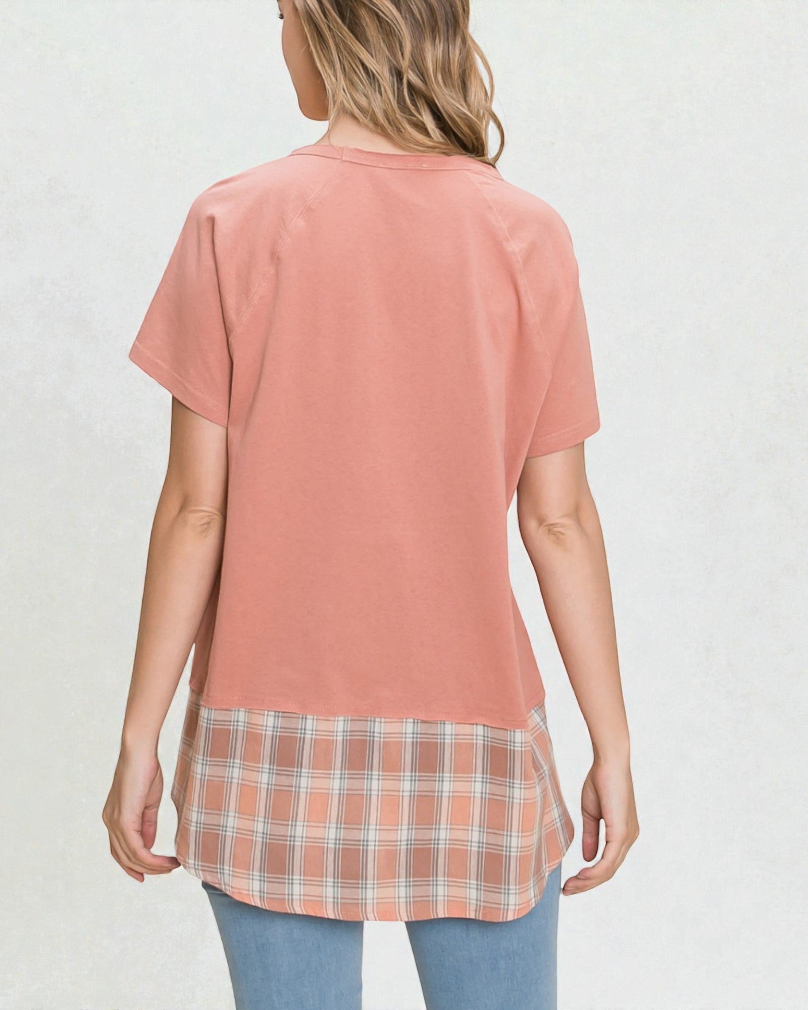 Woman wearing a pink layered shirt with plaid bottom on a white background