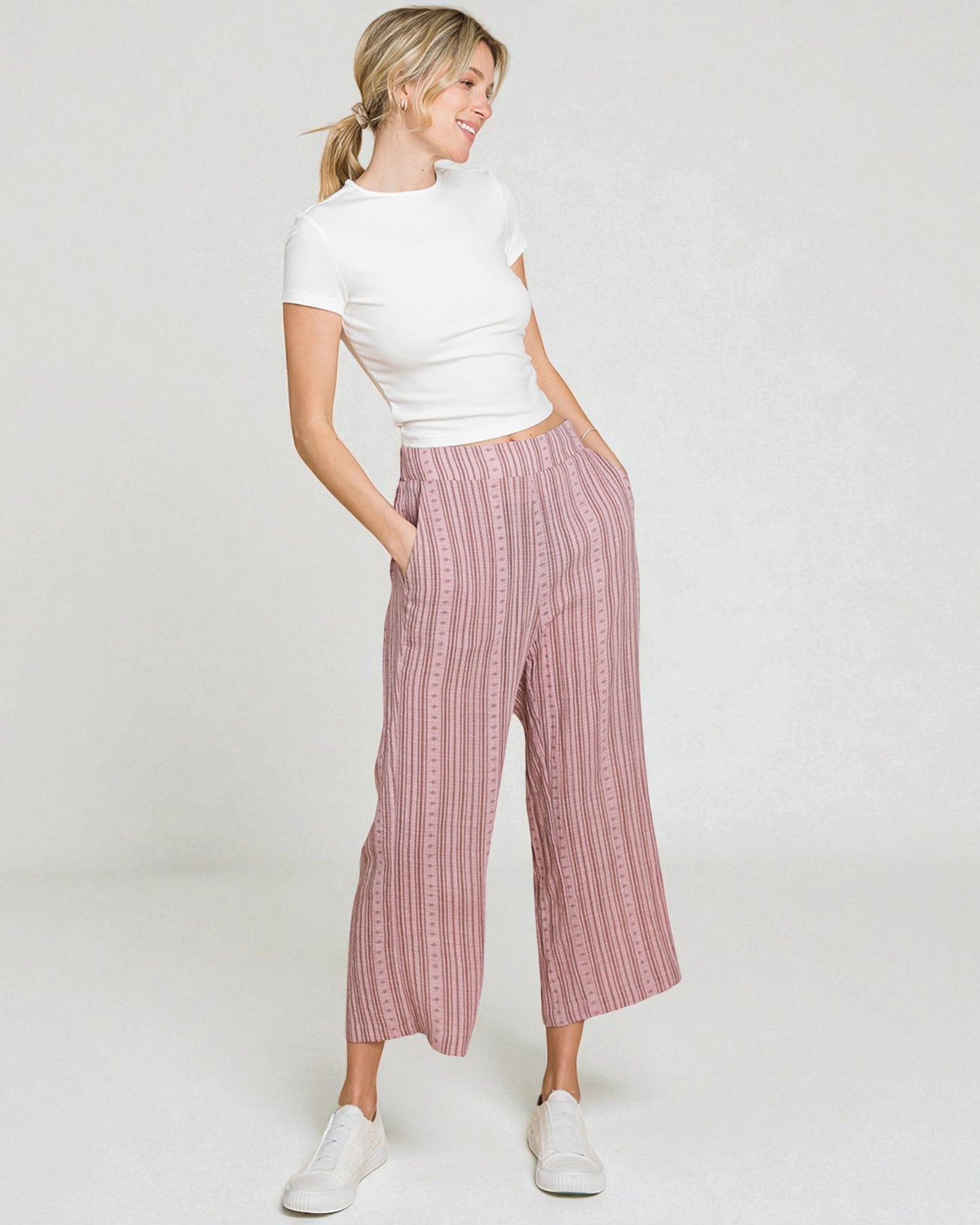 Woman wearing a white top and pink striped pants on a white background