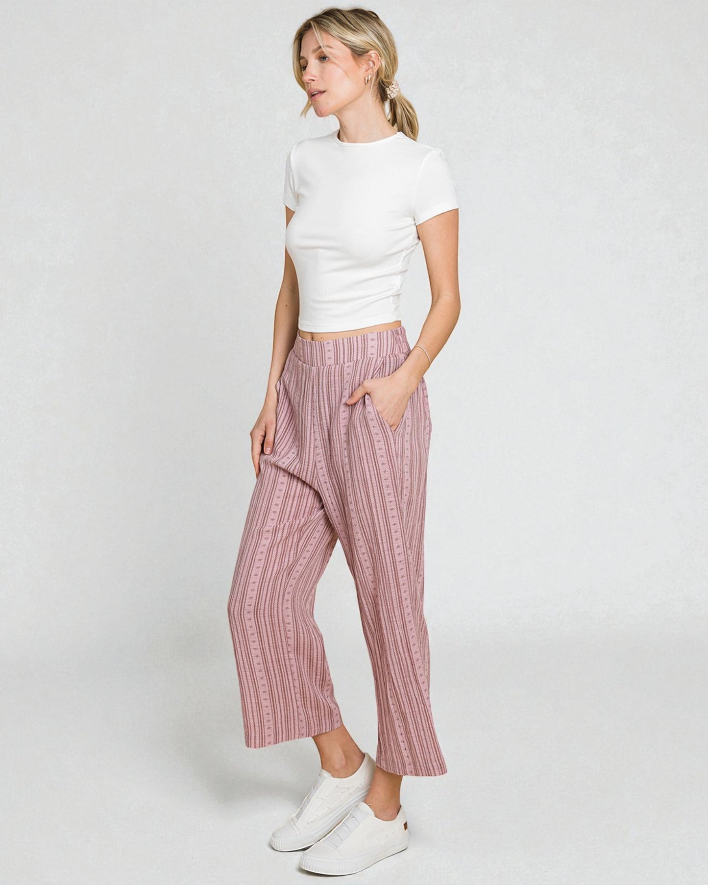 Woman wearing a white top and pink striped pants on a white background