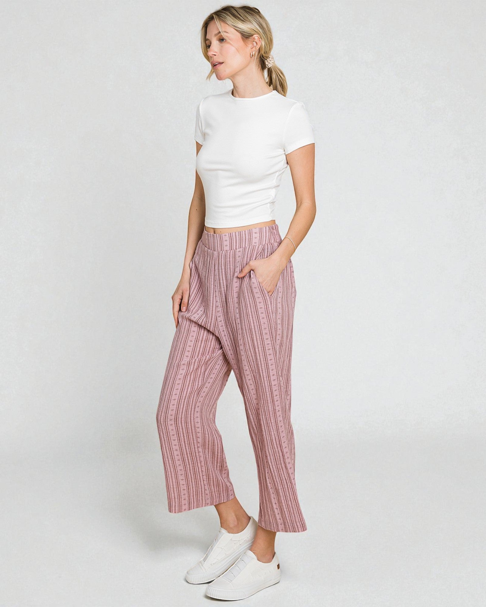 Woman wearing a white top and pink striped pants on a white background