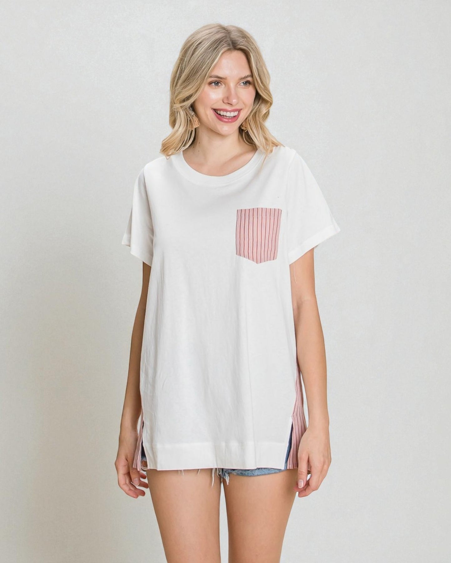 Woman wearing a white t-shirt with a red and white striped pocket on a plain background