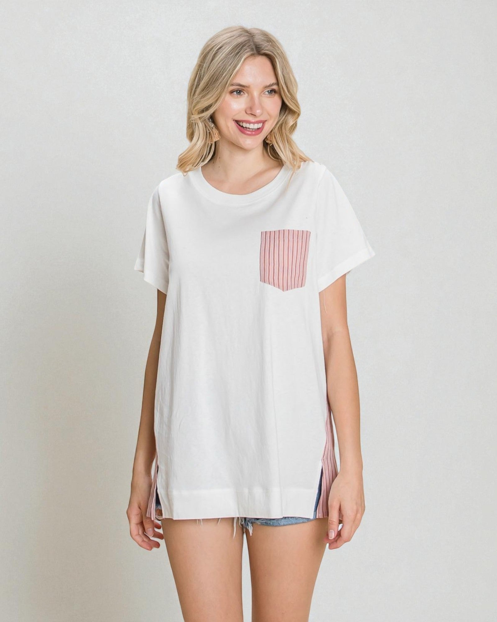 Woman wearing a white t-shirt with a red and white striped pocket on a plain background