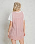 Person wearing a pink striped dress over a white shirt on a plain background