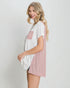Woman wearing a white and pink dress with a pleated design on a plain background