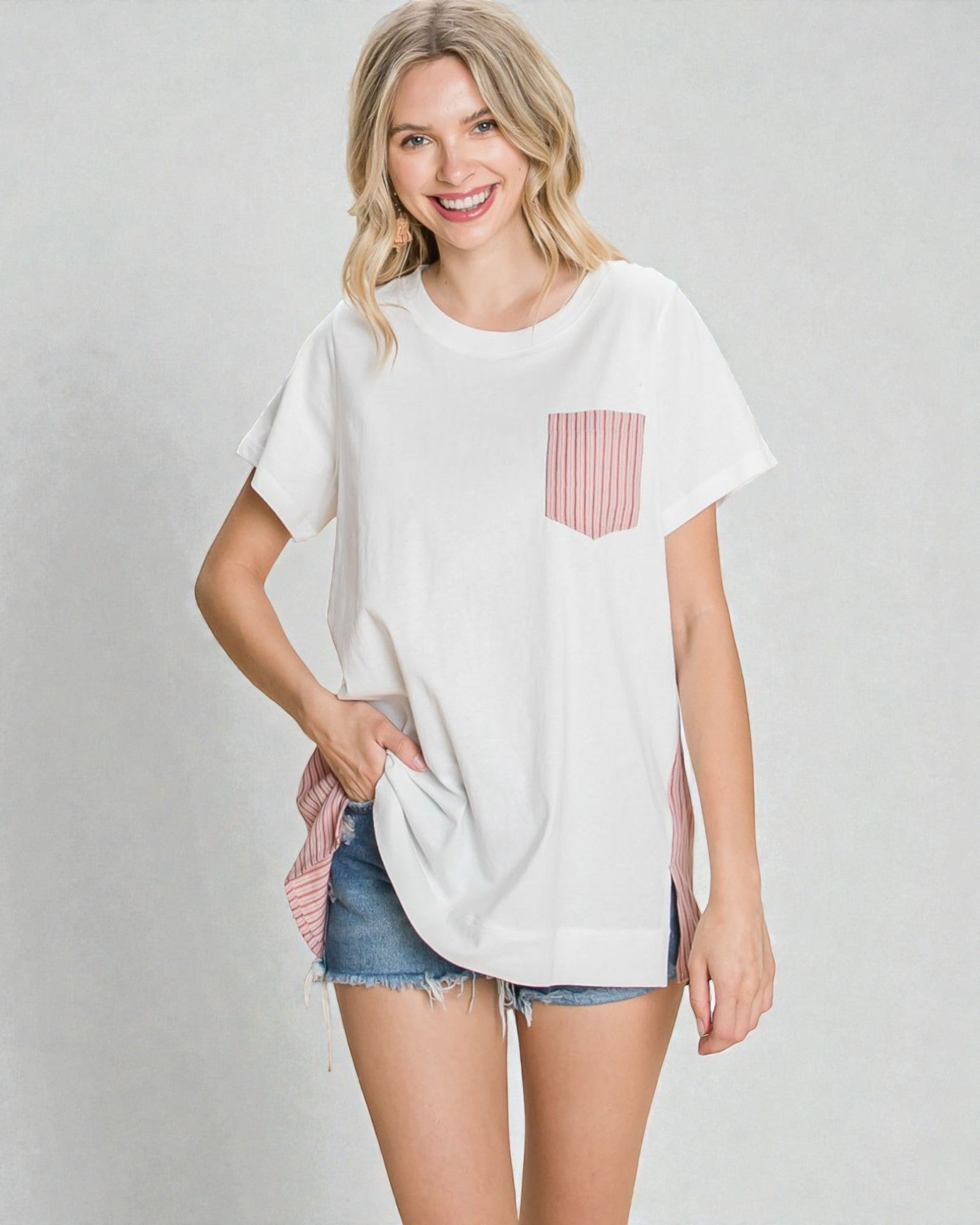 Woman wearing a white t-shirt with a pink pocket design on a plain background