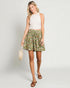 Woman wearing a floral skirt and white top on a plain background