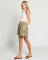 Woman wearing a white top and floral skirt on a plain background