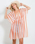Woman wearing a striped orange and white cover-up with a straw hat on a plain background