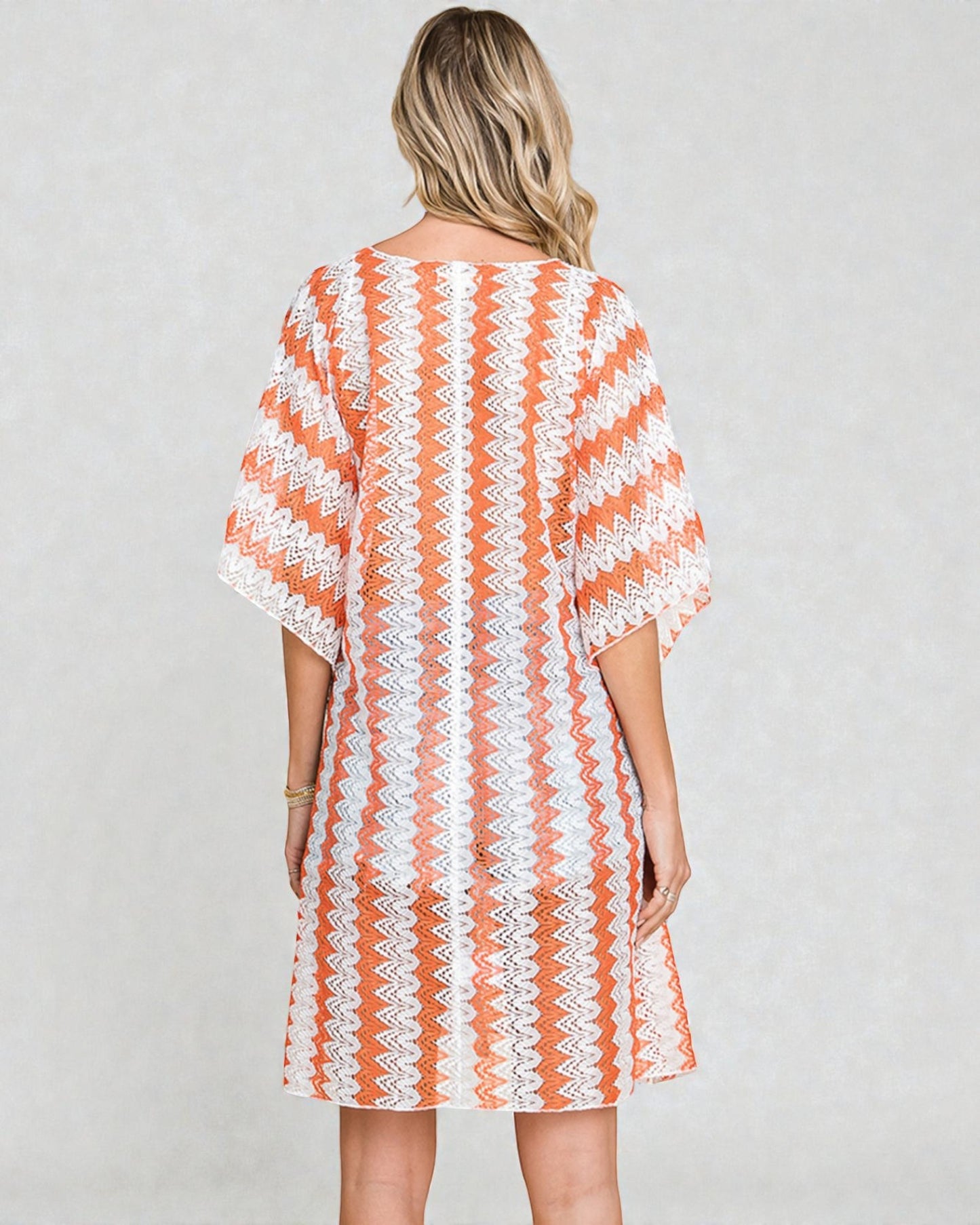 Woman wearing a orange and white patterned dress on a plain background