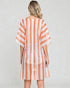 Woman wearing a orange and white patterned dress on a plain background