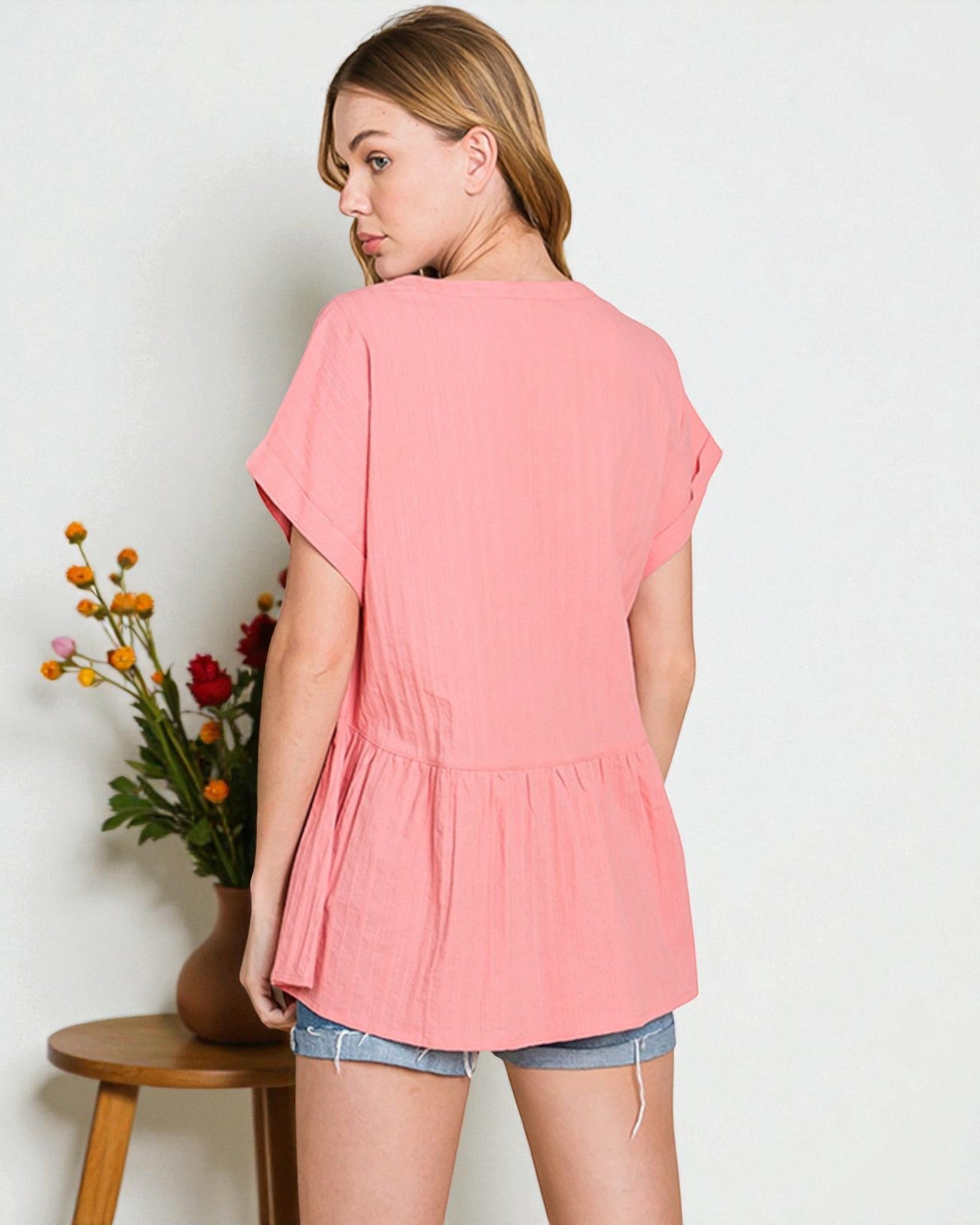 Woman wearing a pink top with a plain background