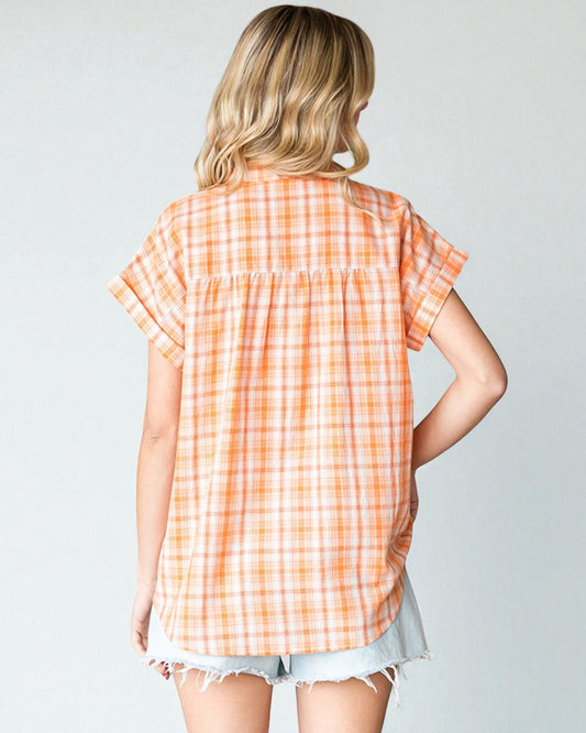 Woman wearing an orange and white checkered shirt against a plain background