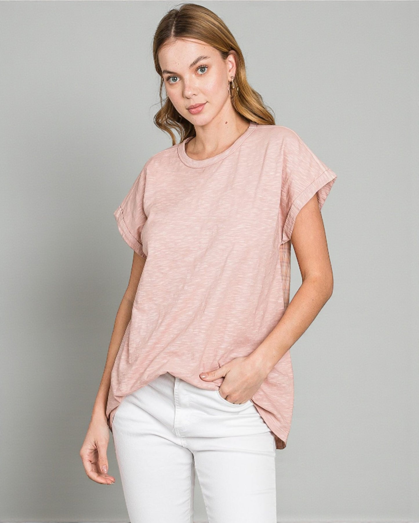 Woman wearing a pink t-shirt and white pants on a gray background